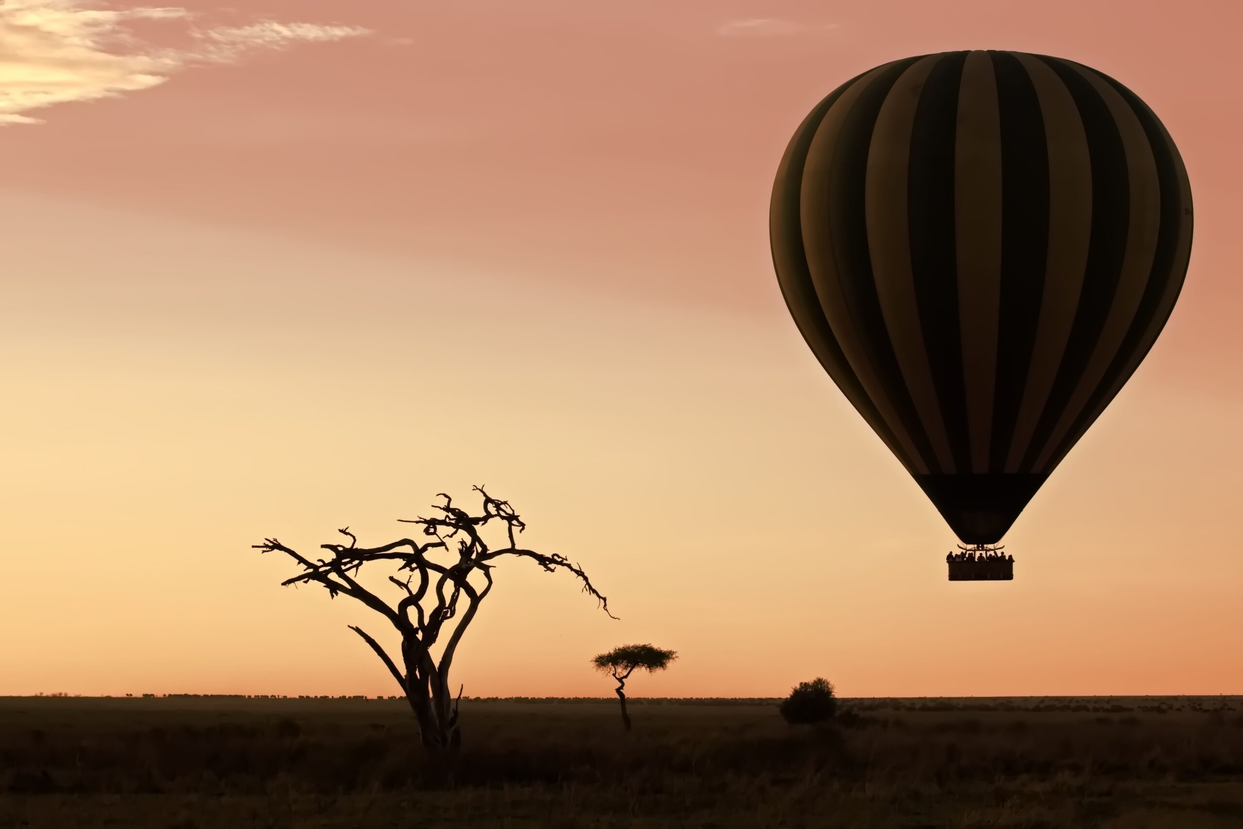 An air balloon flying over a barren landscape at sunset Serengeti, Tanzania